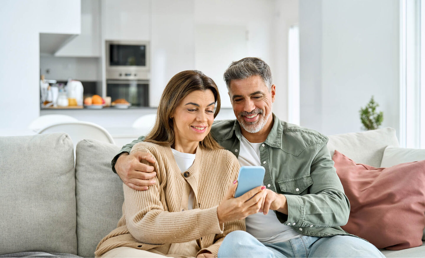 Couple sitting on their couch looking at mobile phone